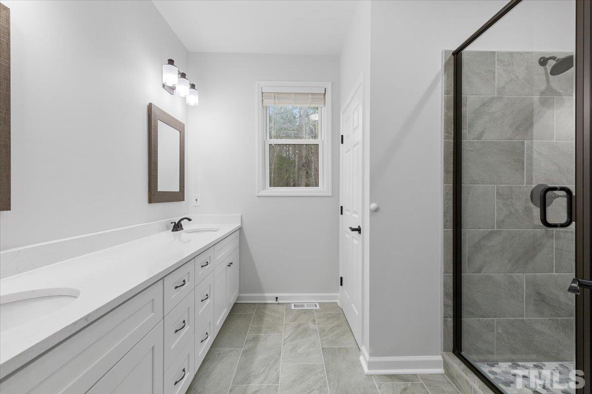 1893 Pilot-Riley Road Zebulon, NC 27597 - Photo 24 of 50 a bathroom with a double vanity sink a mirror and a shower