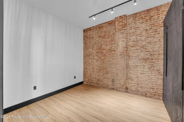 a view of a hallway with wooden floor and a bathroom