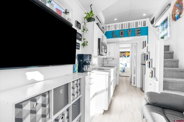 a kitchen with stainless steel appliances a refrigerator a sink dishwasher and white cabinets with wooden floor