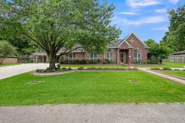 a view of a house with a big yard potted plants and large tree