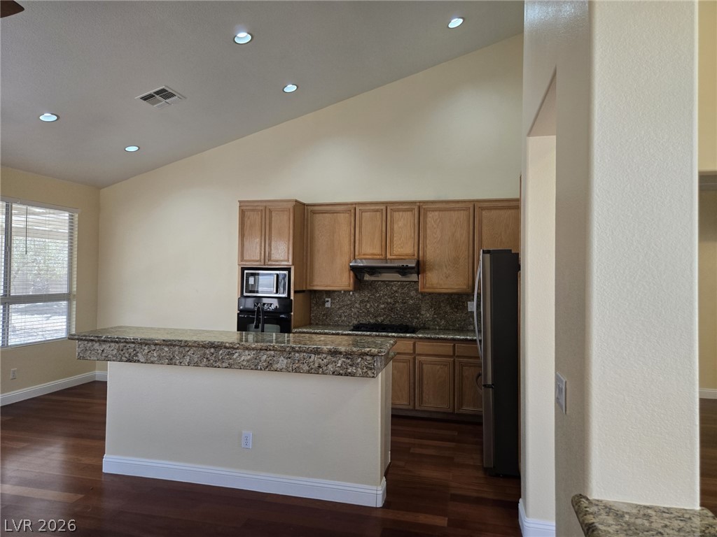 8417 San Ramon Drive Las Vegas, NV 89147 - Photo 12 of 33 Granite counters and rich hardwood flooring create an inviting culinary space under a vaulted ceiling.