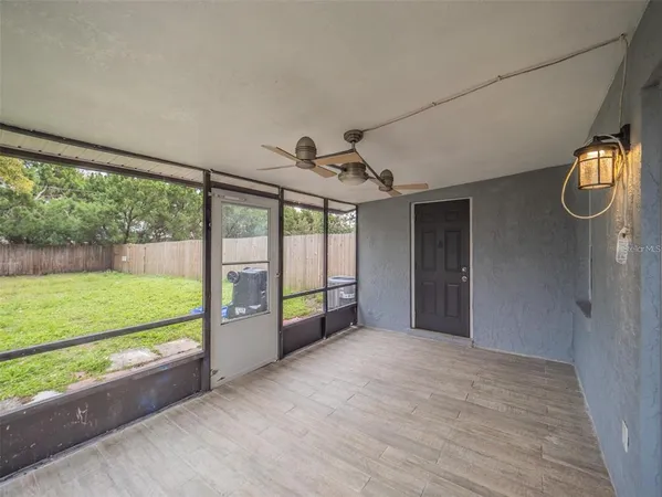 a view of an empty room with a window and a ceiling fan