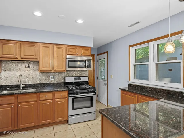 a kitchen with stainless steel appliances granite countertop a stove a sink and a microwave