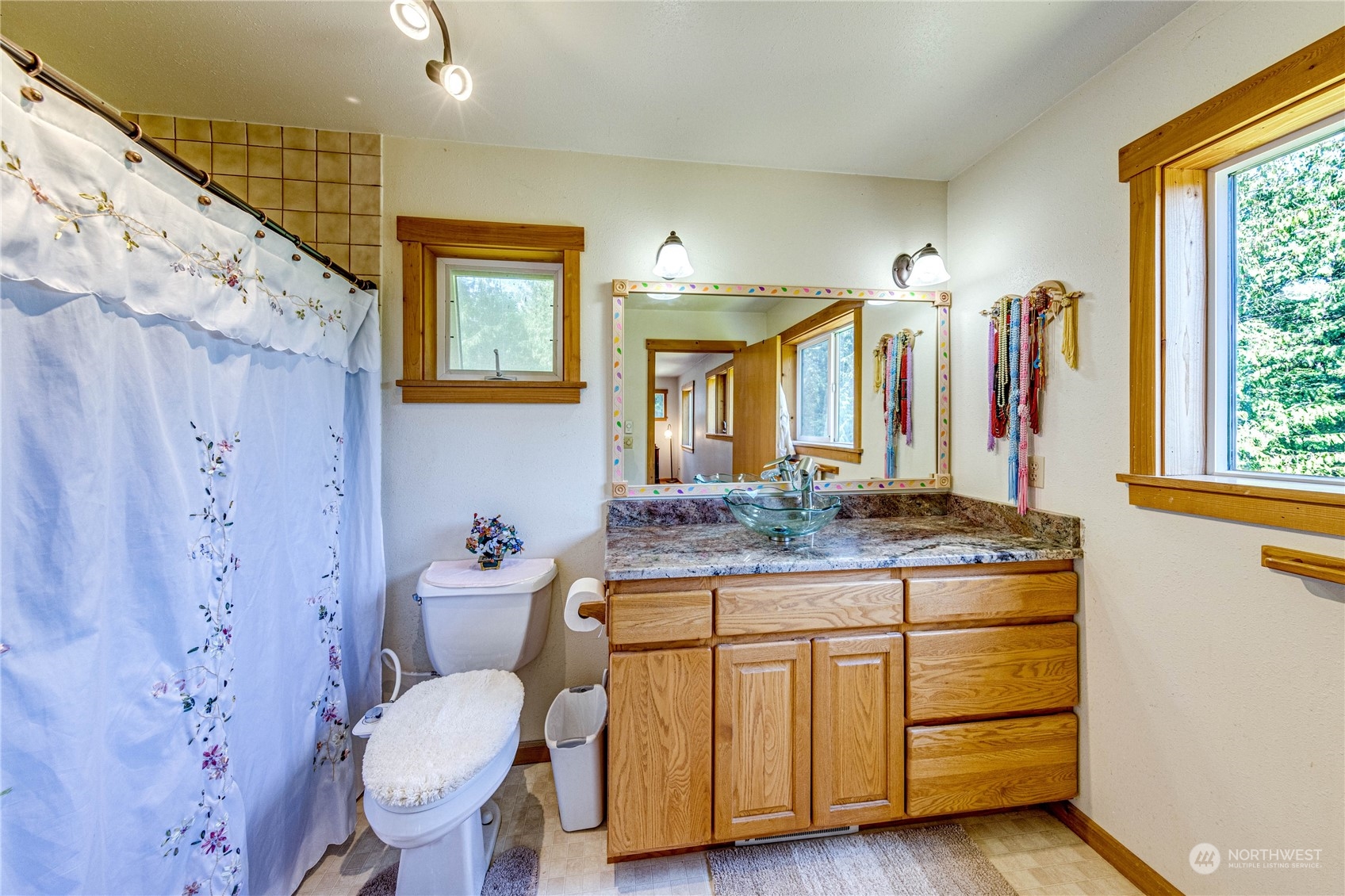 443 Westridge Road Port Angeles, WA 98363 - Photo 26 of 40 a bathroom with a granite countertop sink a toilet a mirror and shower curtain
