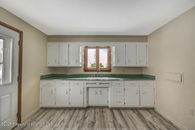 a view of a kitchen with wooden floor and cabinets