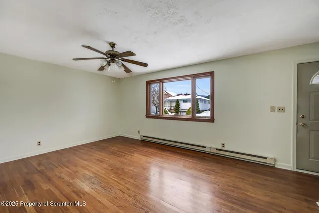an empty room with wooden floor and ceiling fan