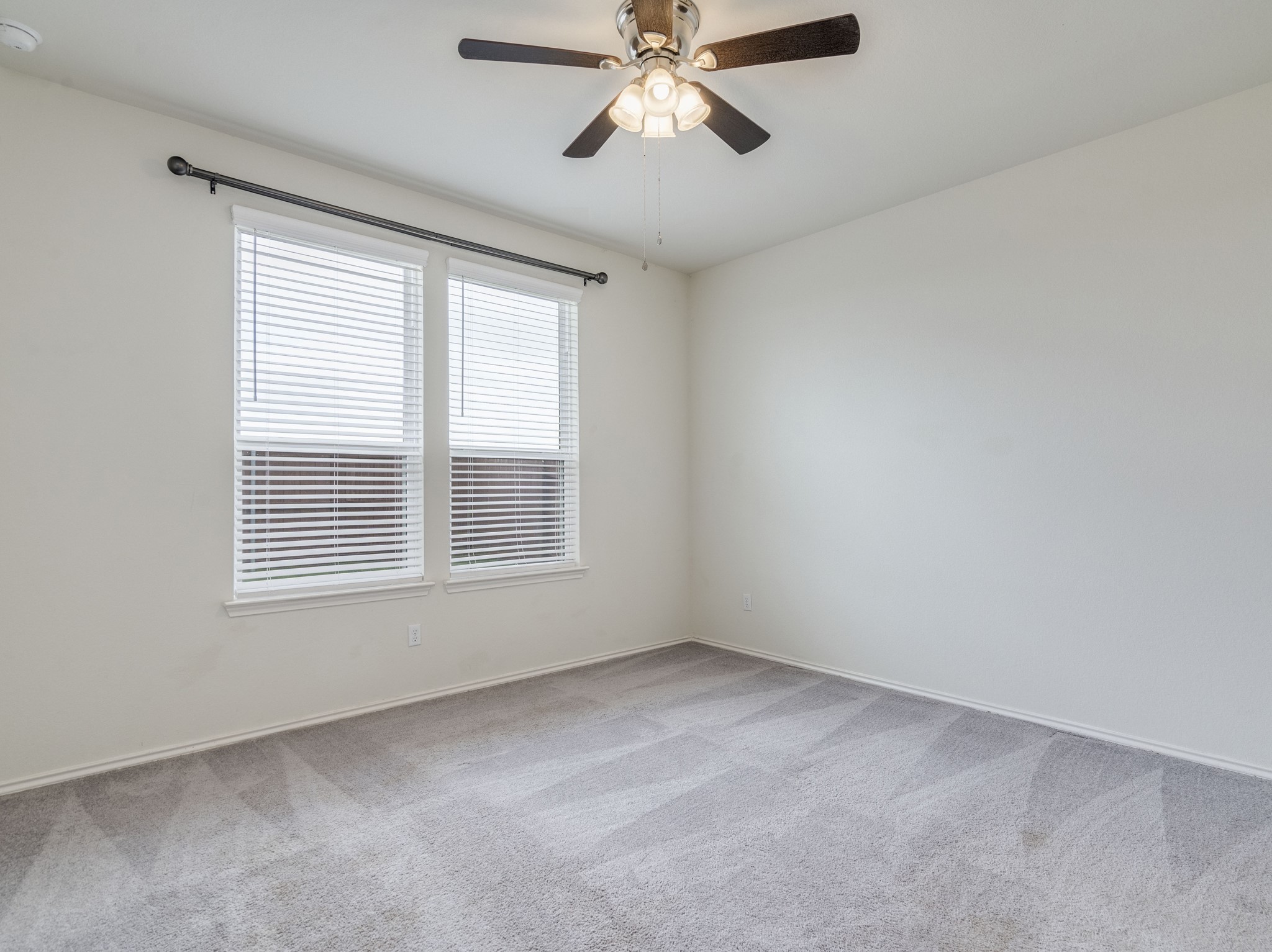 790 Pepperbark Loop Buda, TX 78610 - Photo 8 of 22 An airy bedroom with dual windows and a modern ceiling fan.