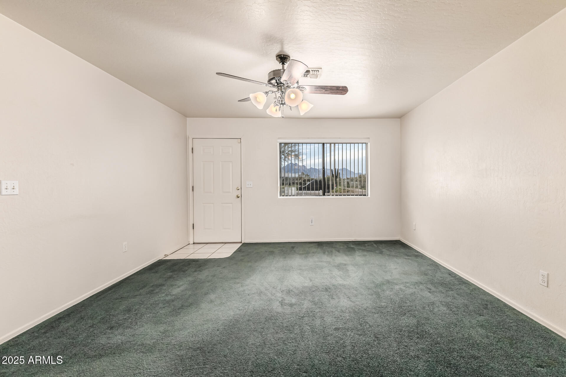 1008 North Meridian Drive Apache Junction, AZ 85120 - Photo 11 of 38 an empty room with a chandelier fan and windows