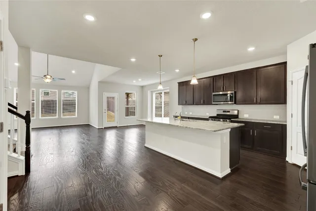 a kitchen with stainless steel appliances granite countertop a sink dishwasher a refrigerator and a stove with wooden floor