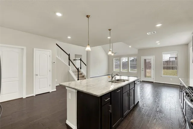 a open kitchen with a sink a island a stove and wooden floor