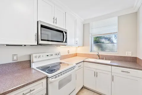 a kitchen with granite countertop cabinets stainless steel appliances a sink and a window