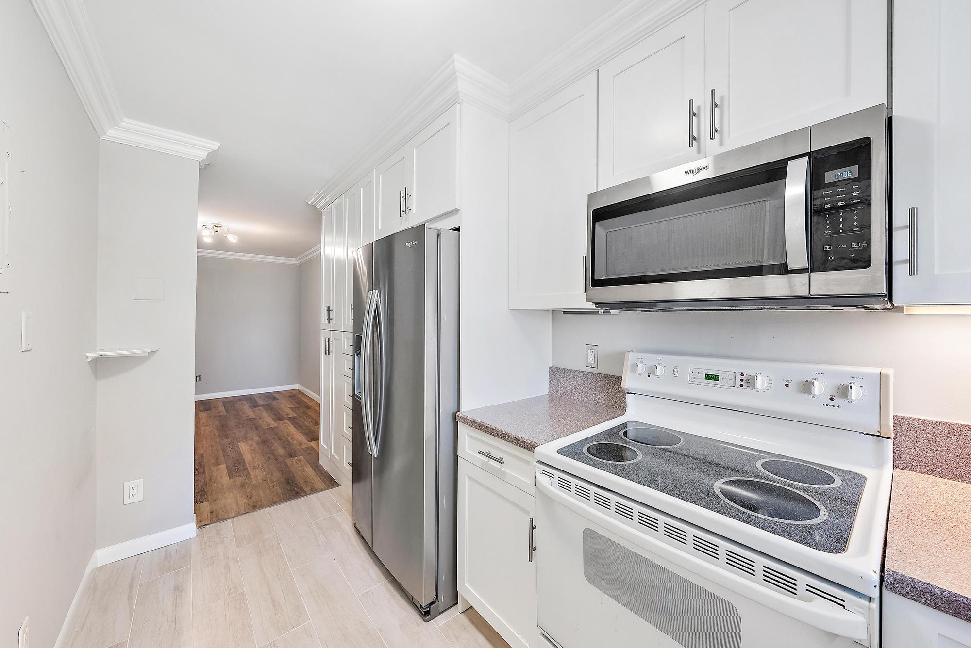 109 Paradise Harbour Boulevard, Unit 307 North Palm Beach, FL 33408 - Photo 7 of 20 a kitchen with stainless steel appliances a stove a microwave and cabinets