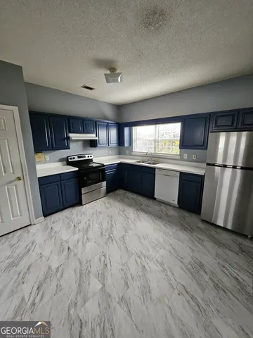 a large kitchen with stainless steel appliances granite countertop a stove refrigerator and cabinets