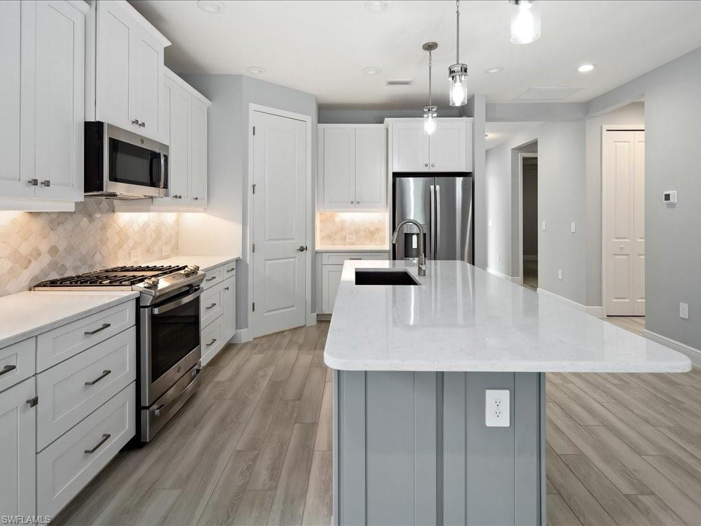 2119 Marquesa Circle Naples, FL 34112 - Photo 12 of 44 a kitchen with stainless steel appliances kitchen island granite countertop a stove a sink and a refrigerator