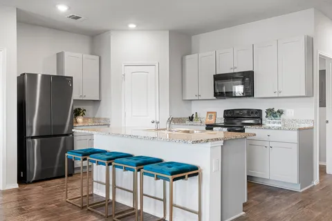 a kitchen with stainless steel appliances granite countertop a stove top oven a sink dishwasher and a refrigerator with wooden floor