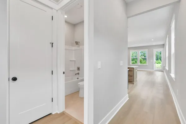 a view of a hallway with wooden floor and a bathroom