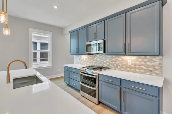 a kitchen with granite countertop a stove a sink and a microwave