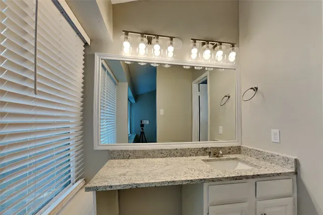 a bathroom with a granite countertop sink and a mirror