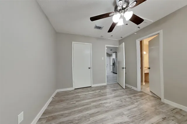 a view of an empty room and chandelier fan
