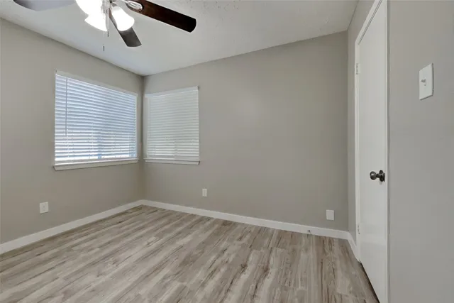 a view of room with window ceiling fan and hardwood floor
