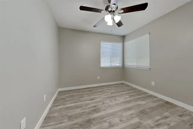 an empty room with windows and fan
