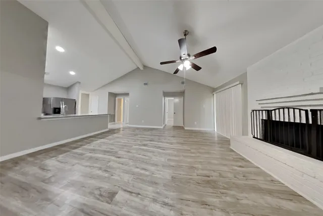 a view of an empty room with chandelier fan and windows
