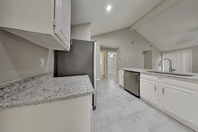 a large kitchen with granite countertop a sink and white cabinets