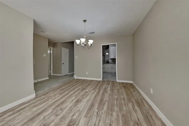 wooden floor in an empty room with a chandelier