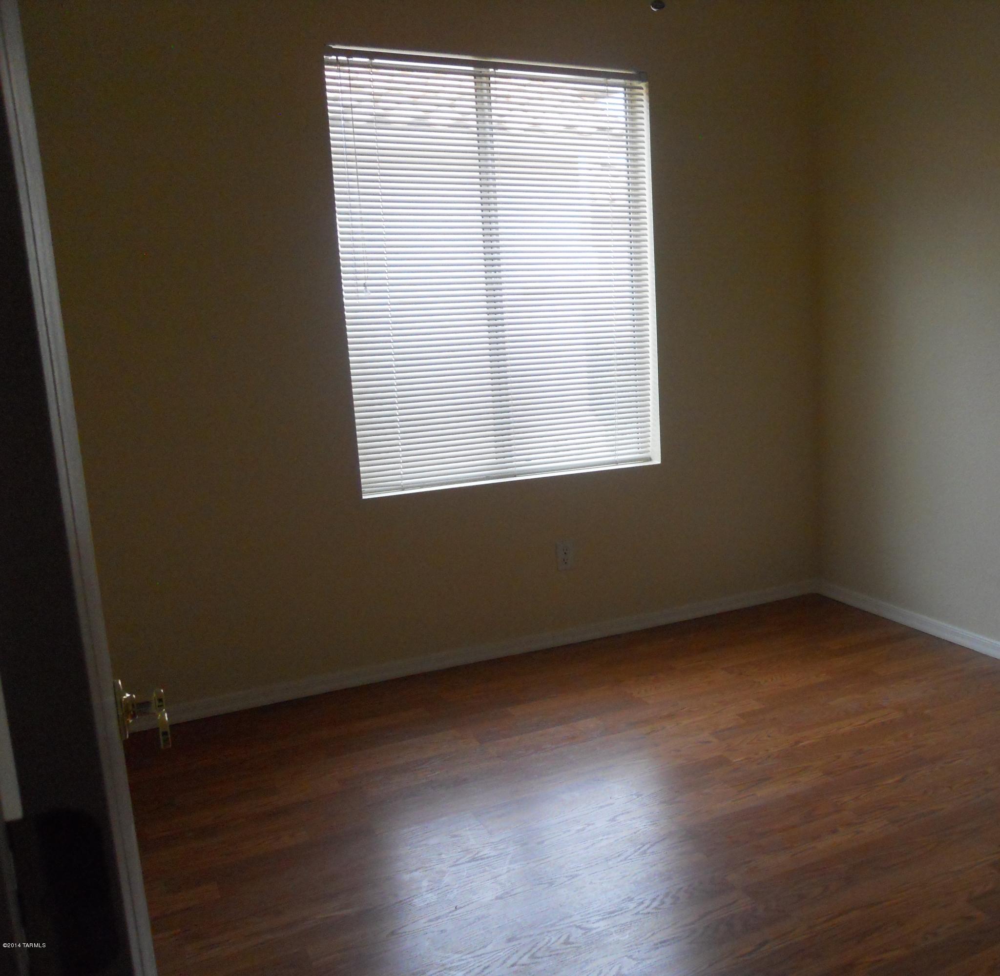 7736 East Elk Creek Road Tucson, AZ 85750 - Photo 4 of 11 an empty room with wooden floor and a window