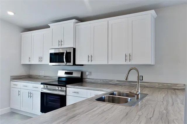 a kitchen with granite countertop white cabinets and stainless steel appliances
