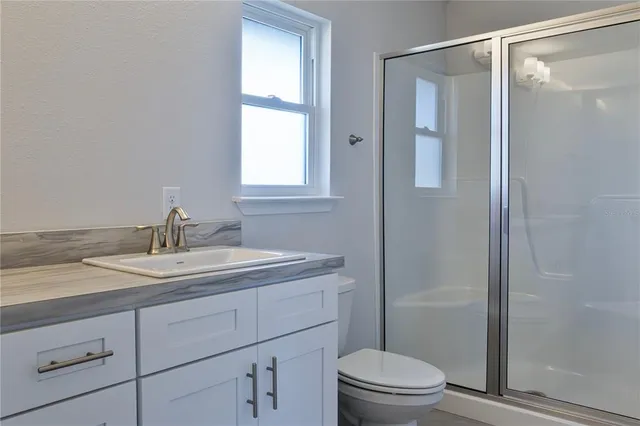 a bathroom with a sink a toilet and shower