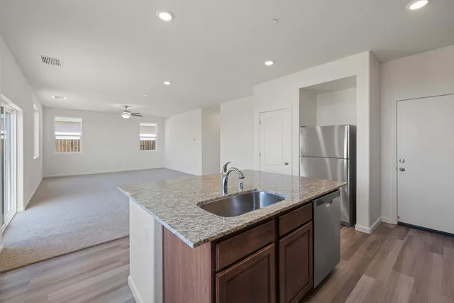 a kitchen with stainless steel appliances granite countertop a sink and dishwasher a refrigerator with wooden floor