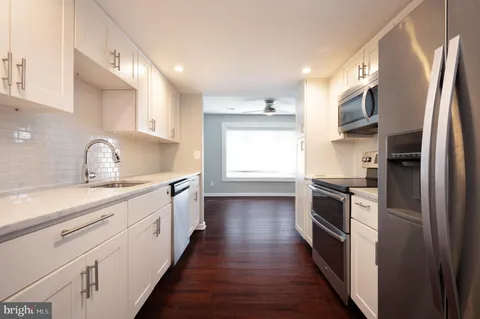 a kitchen with stainless steel appliances a sink dishwasher a refrigerator and a stove with wooden floors