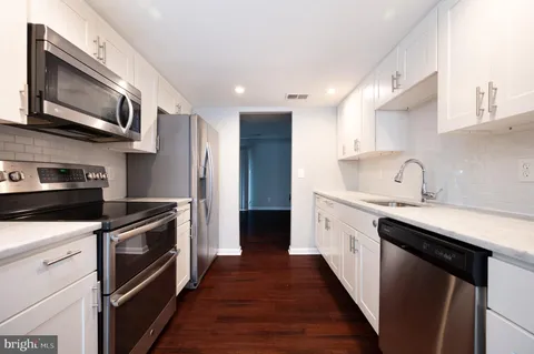 a kitchen with stainless steel appliances granite countertop a sink a stove top oven and refrigerator