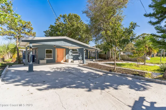 a view of a house with backyard and a tree