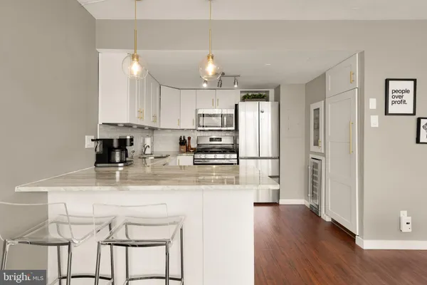 a kitchen with stainless steel appliances granite countertop a refrigerator a sink dishwasher a stove and white cabinets with wooden floor