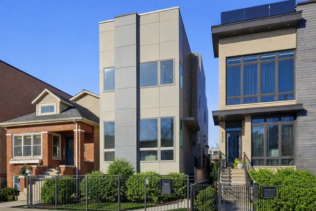 front view of a brick house with a large window and potted plants