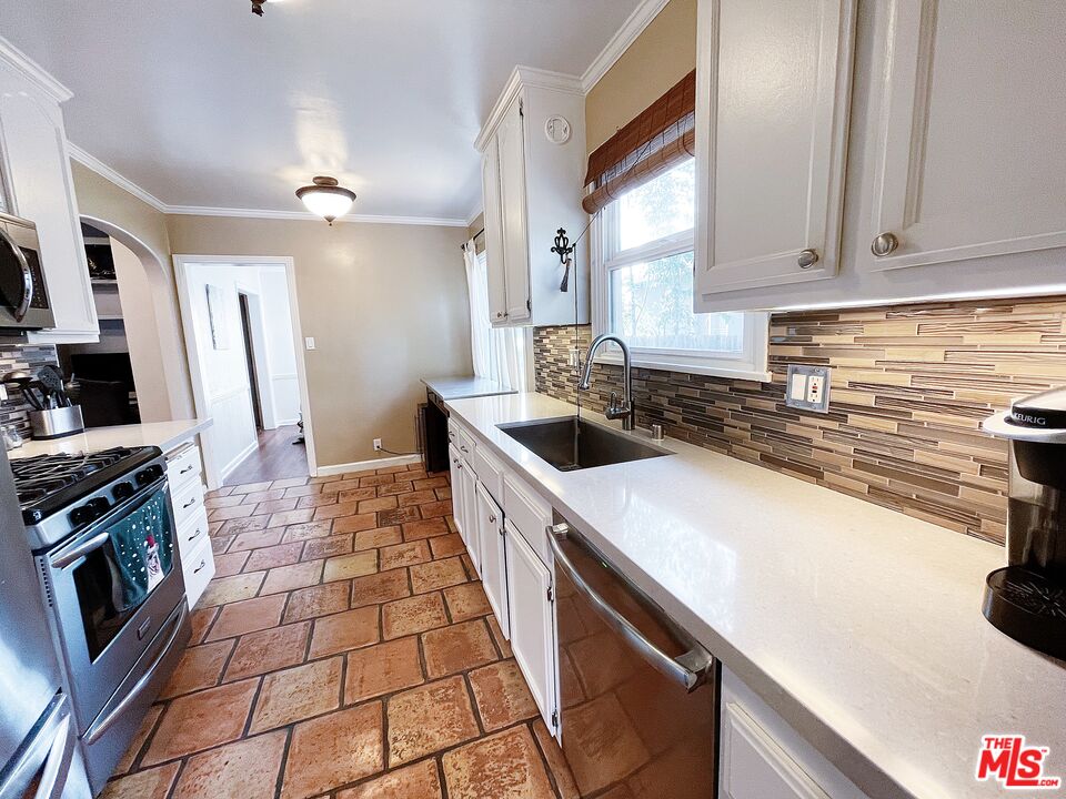 6464 Newcastle Avenue Reseda, CA 91335 - Photo 7 of 17 a kitchen with a sink a stove top oven and cabinetry