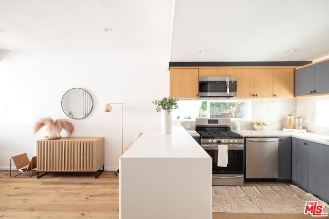 a kitchen with stainless steel appliances a sink a stove a microwave a sink a refrigerator and cabinets