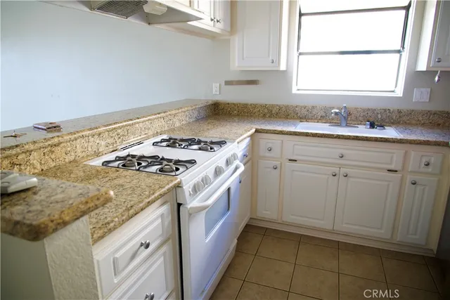 a kitchen with granite countertop a sink stove and cabinets