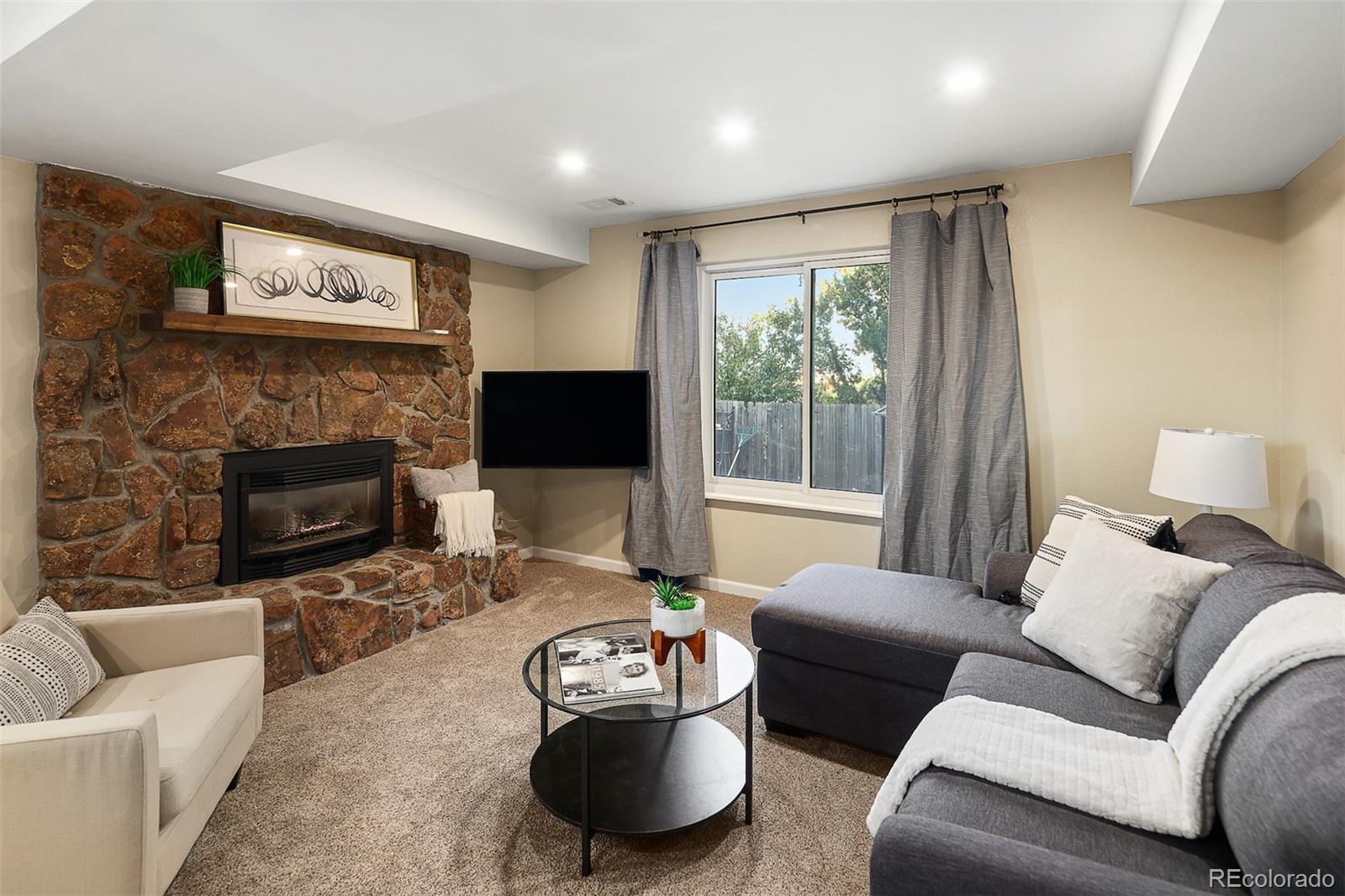 10499 Newcombe Street Westminster, CO 80021 - Photo 17 of 33 a living room with furniture a large window and a fireplace