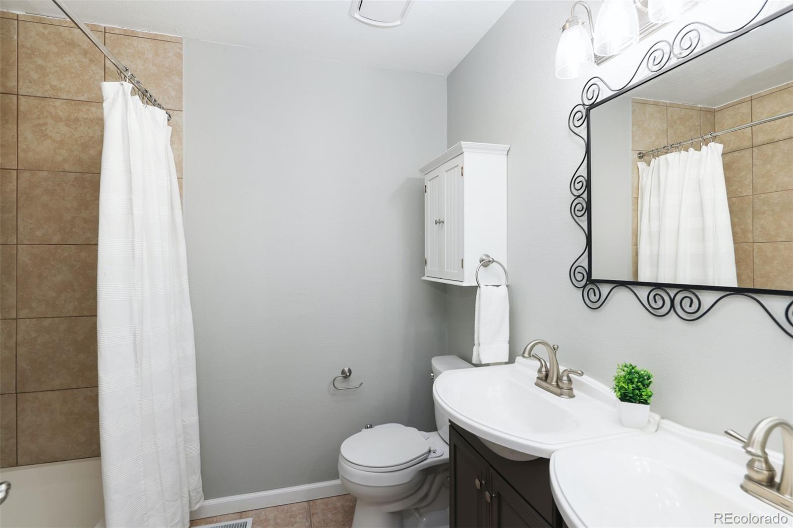 10499 Newcombe Street Westminster, CO 80021 - Photo 24 of 33 a bathroom with a granite countertop sink a toilet and a mirror