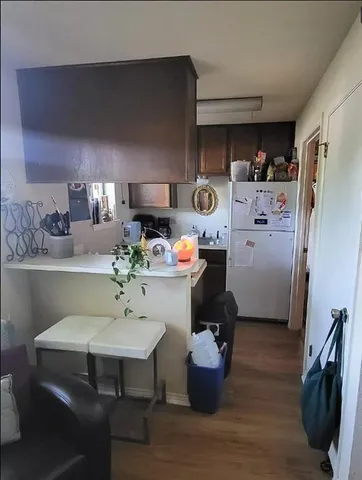a room with stainless steel appliances a kitchen island hardwood floor and a sink