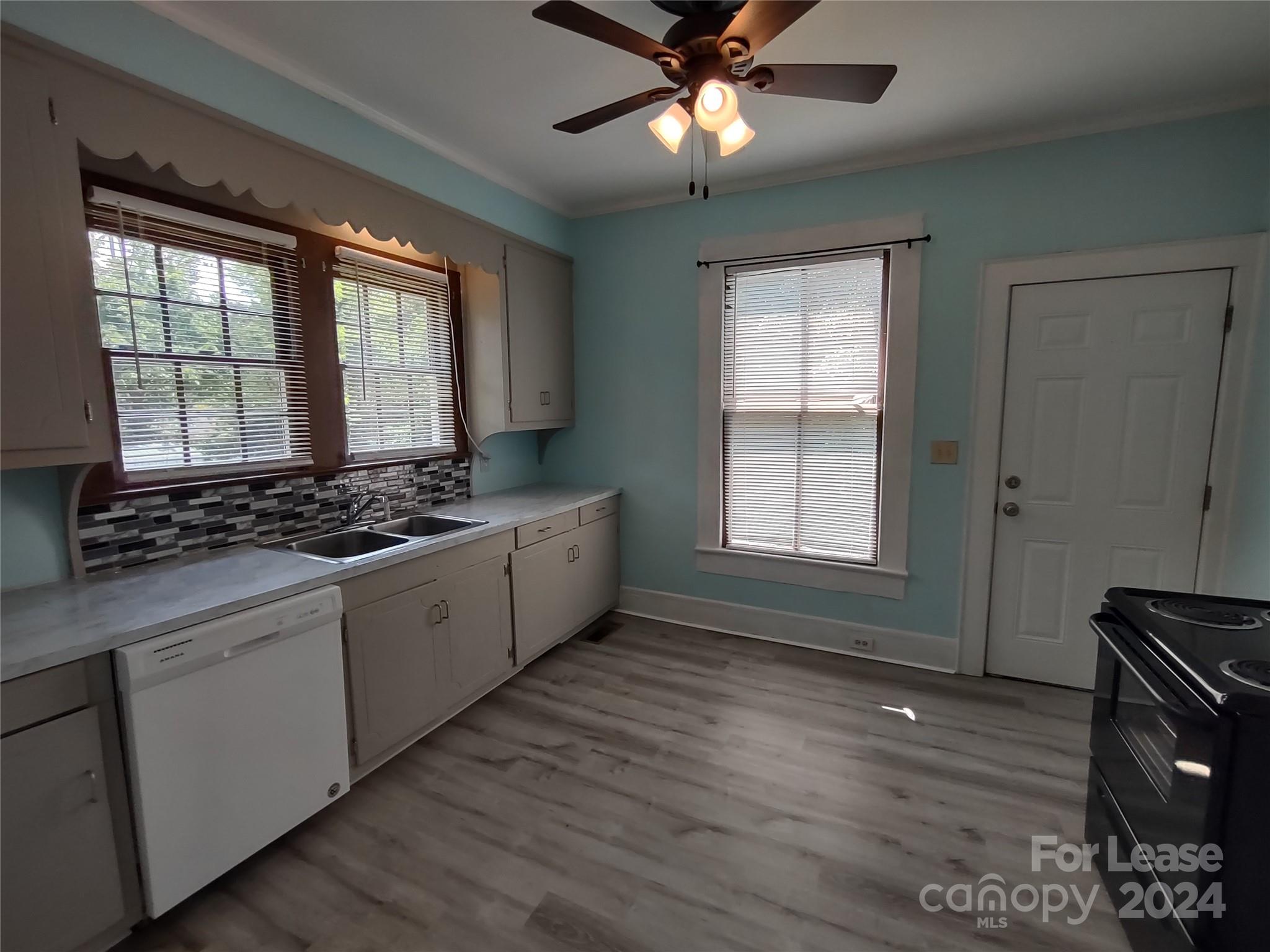 476 Spring Street Southwest Concord, NC 28025 - Photo 2 of 12 a kitchen with stainless steel appliances kitchen island granite countertop a stove a sink and white cabinets with wooden floor next to windows