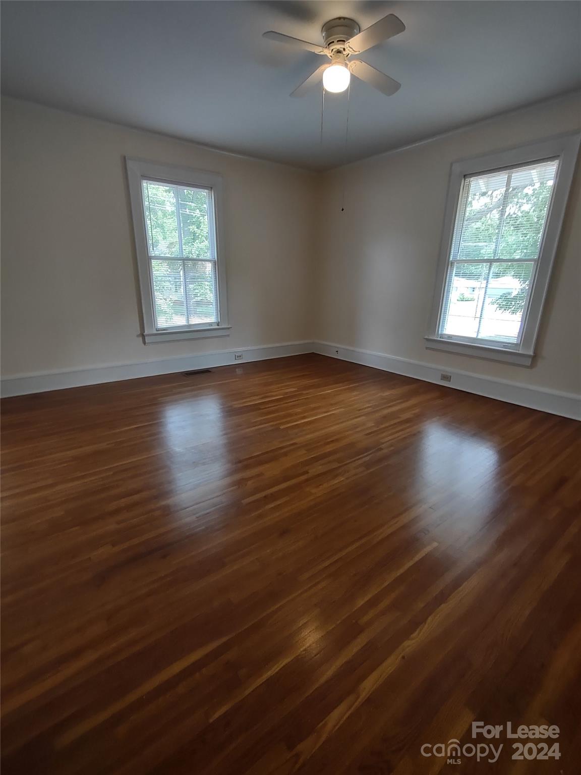 476 Spring Street Southwest Concord, NC 28025 - Photo 9 of 12 an empty room with wooden floor chandelier fan and windows
