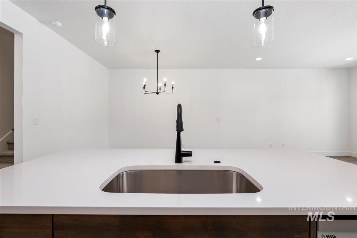 768 South Calhoun Lane Star, ID 83669 - Photo 16 of 36 Kitchen island featuring a stainless steel undermount sink, matte black faucet, and white countertop