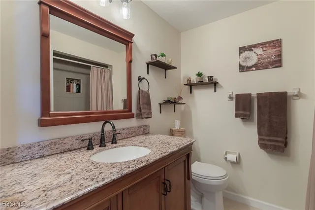 a bathroom with a granite countertop sink vanity mirror and toilet