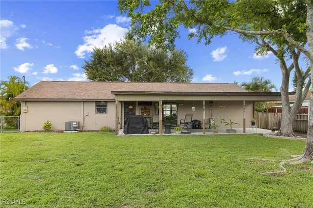 a view of a house with a yard and a large tree