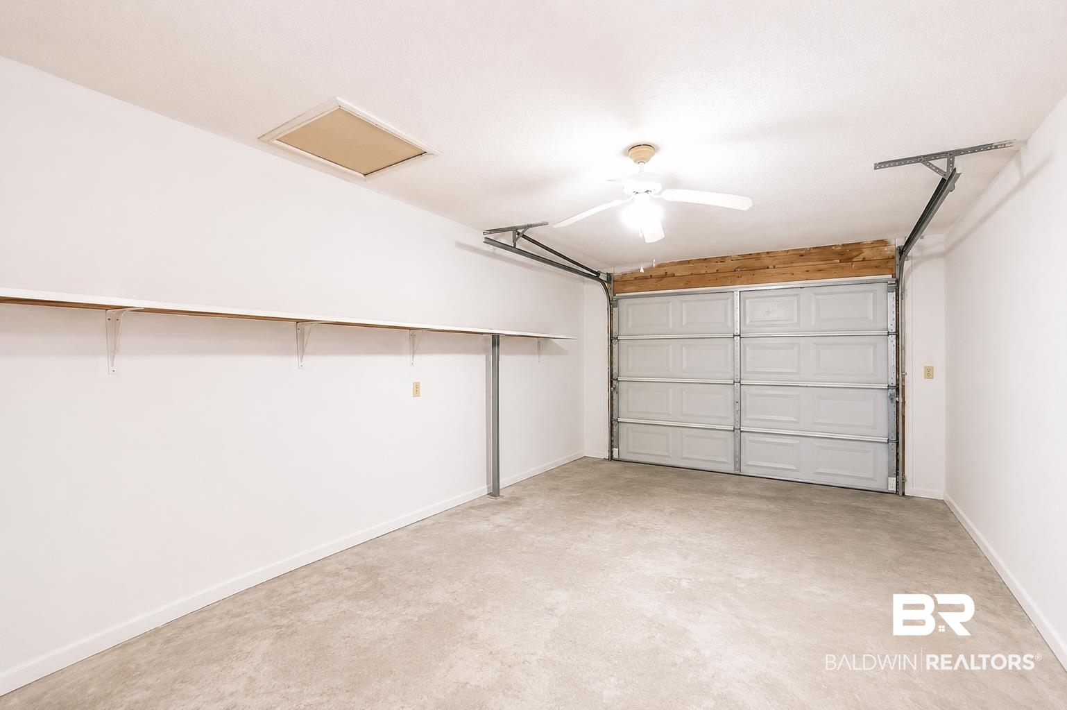 614 East Gate Circle Foley, AL 36535 - Photo 15 of 31 Spacious garage featuring a concrete floor, built-in shelving, a ceiling fan, a garage door, and an attic access panel