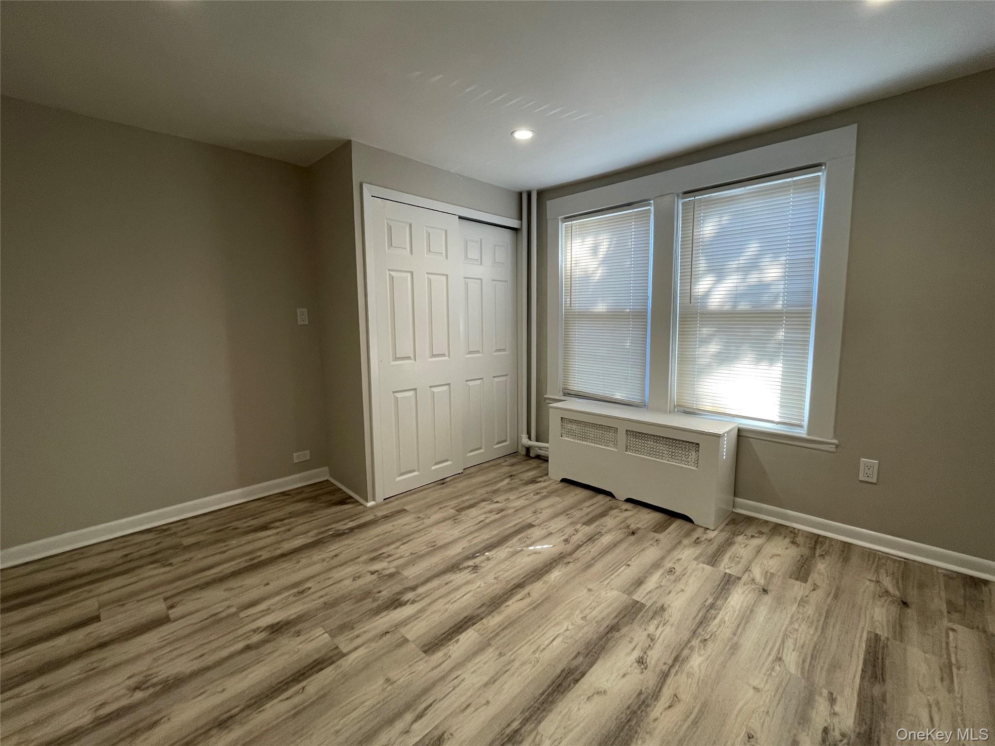 89 2nd Street, Unit 1 New Rochelle, NY 10801 - Photo 11 of 13 Unfurnished bedroom with radiator, light wood-type flooring, a closet, and recessed lighting
